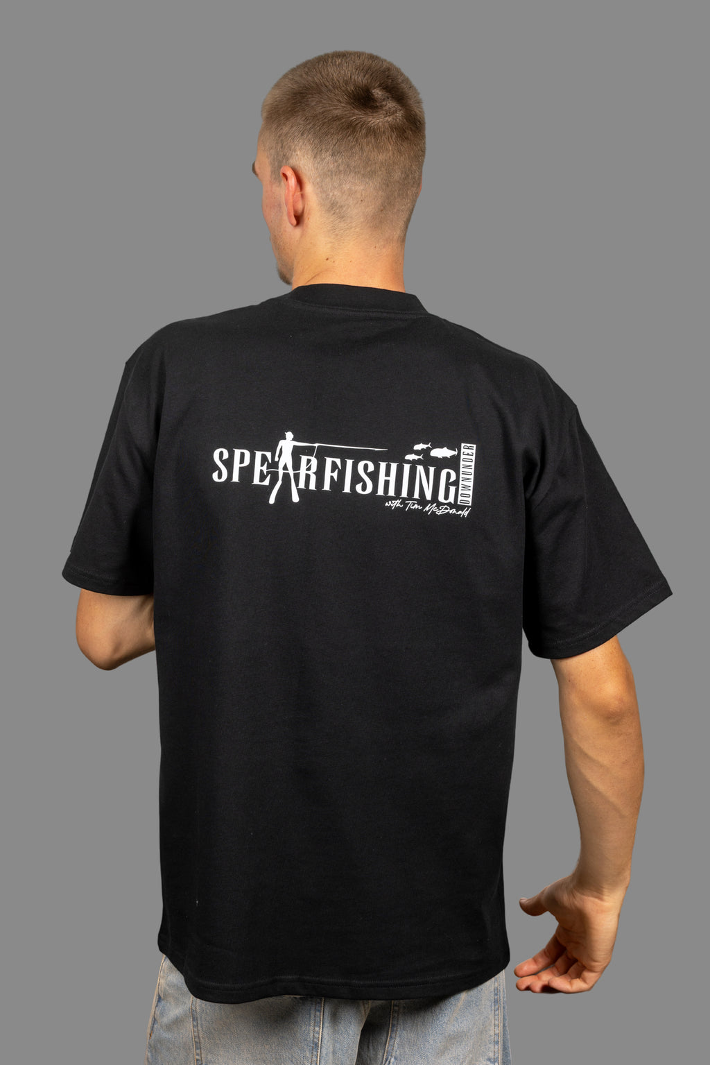 Person wearing a black t-shirt with 'Spearfishing' text on the back, standing against a gray background