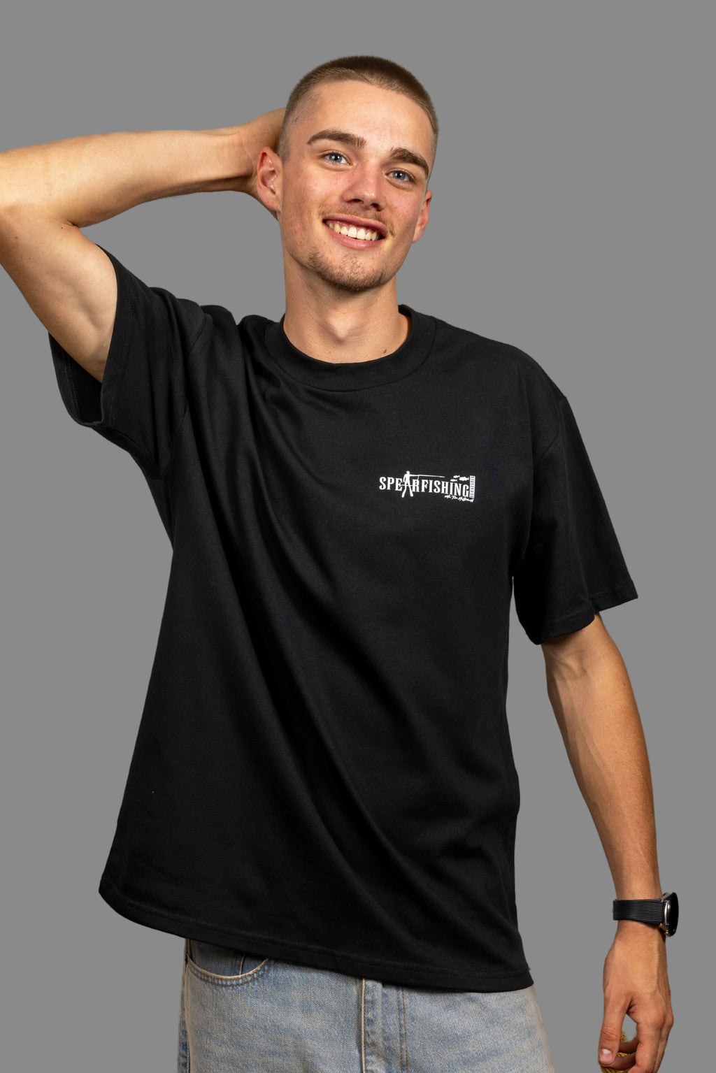 Man wearing a black t-shirt with a logo on a gray background